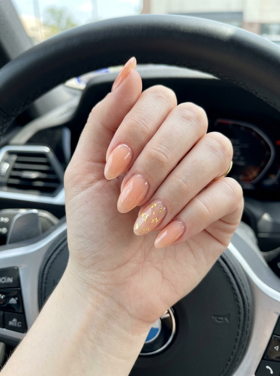 Almond summer nails 2026 for fair skin: Pale peach jelly with gold flake sparkle for bohemian summer events.