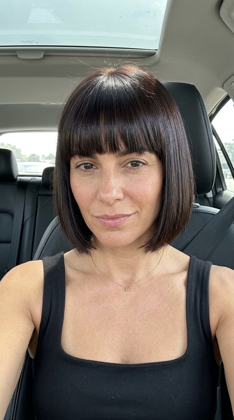 chin-length French bob with espresso brunette, blunt cut, full fringe — sophisticated city break