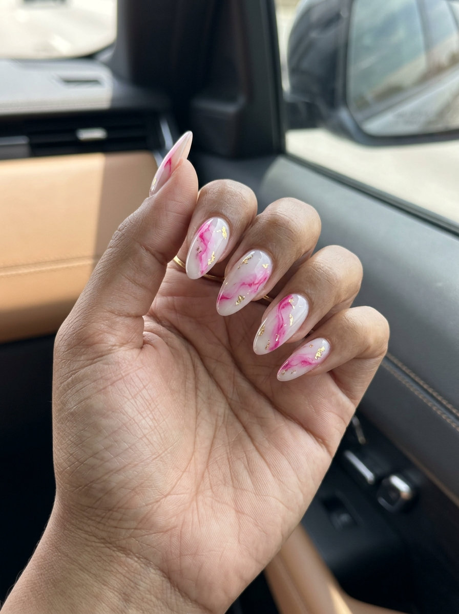 Sophisticated summer hot pink nails designs 2026: Marble with gold accents on almond nails.