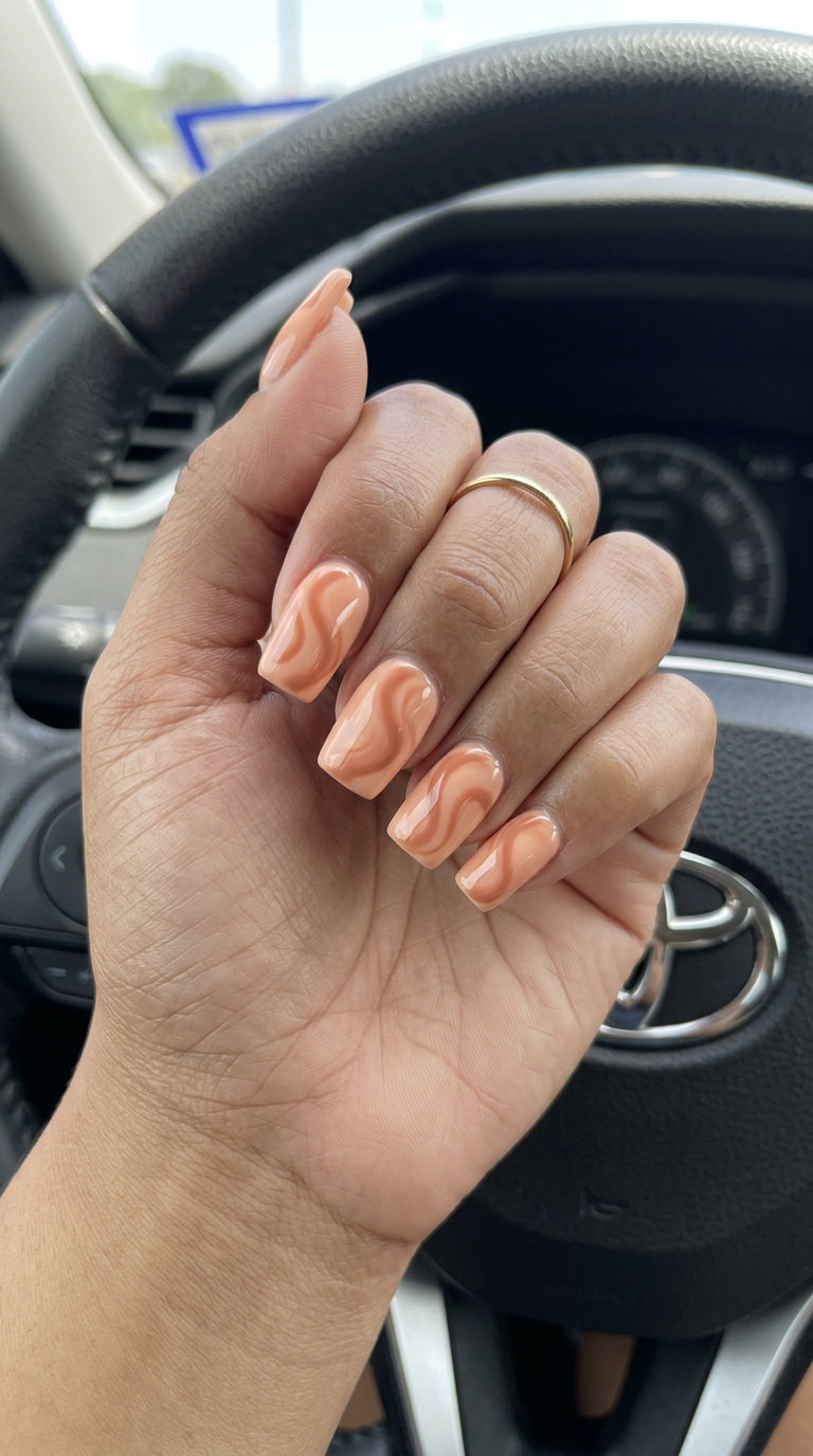 Peach fuzz glossy swirls nails for summer 2026. Medium square, peach fuzz with darker peach abstract swirls. Romantic & playful.