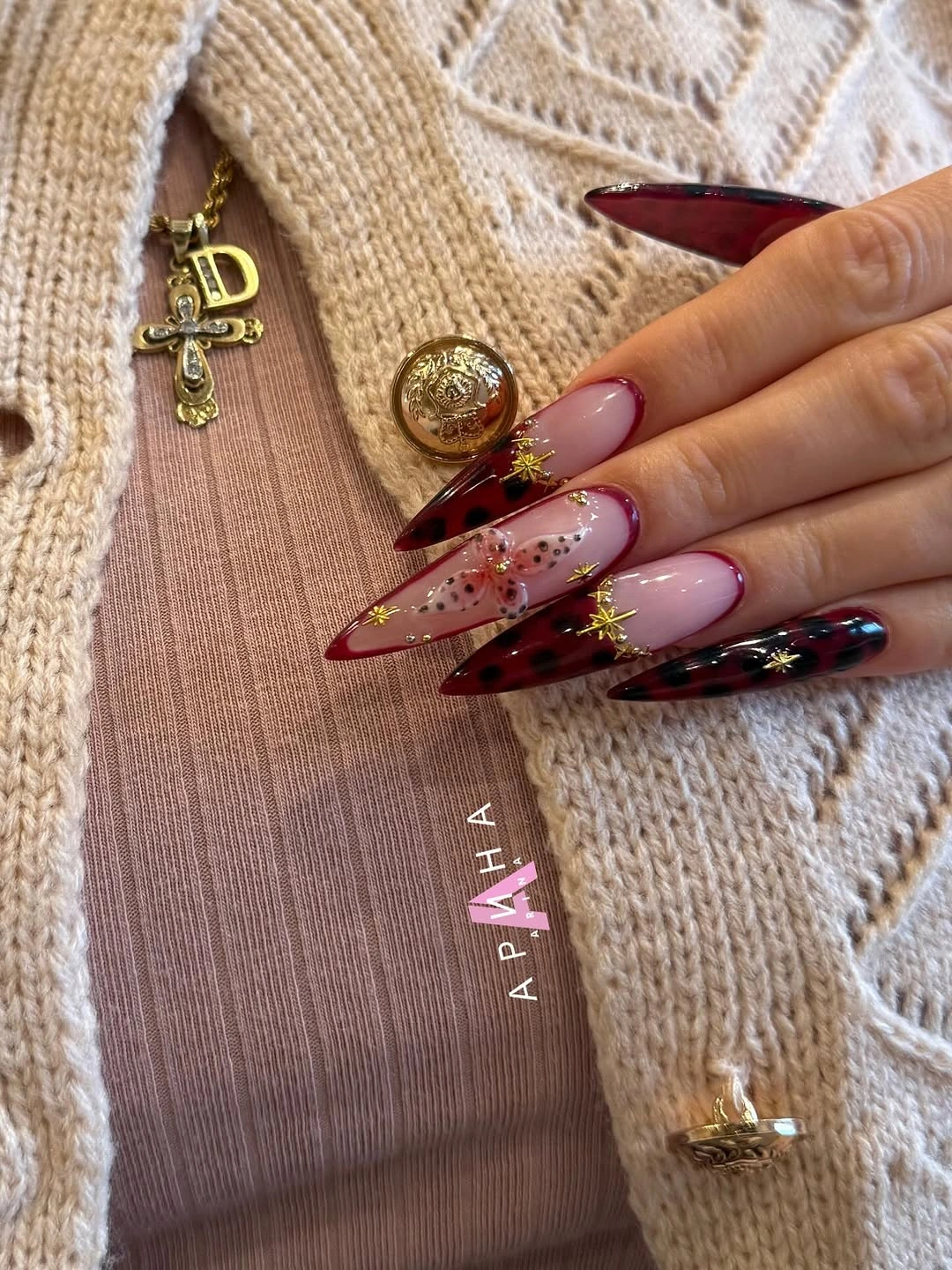 long pointed burgundy pink nails with gold detail