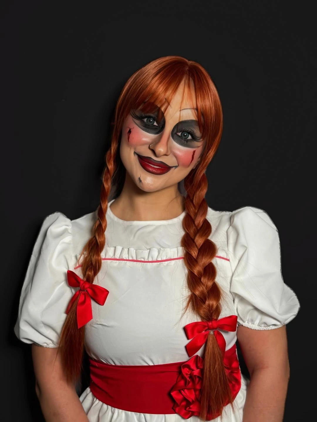 White doll dress with red sash bows and braided red hair