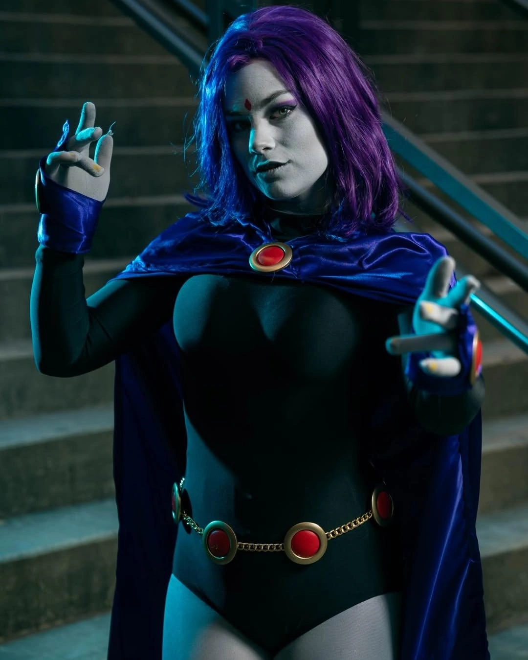 Purple cape over black fitted superhero-inspired costume with gem belt