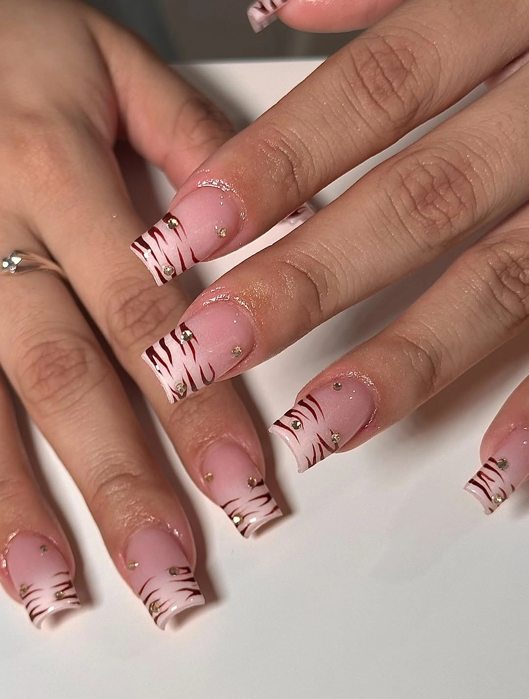 Pink square nails with layered chocolate tip lines