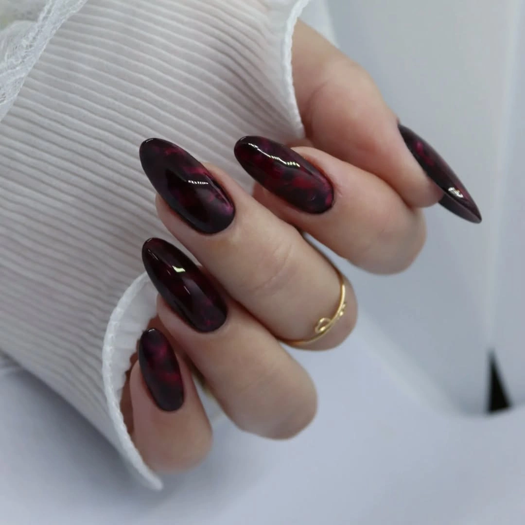 Glossy blackened burgundy almond nails with red undertones