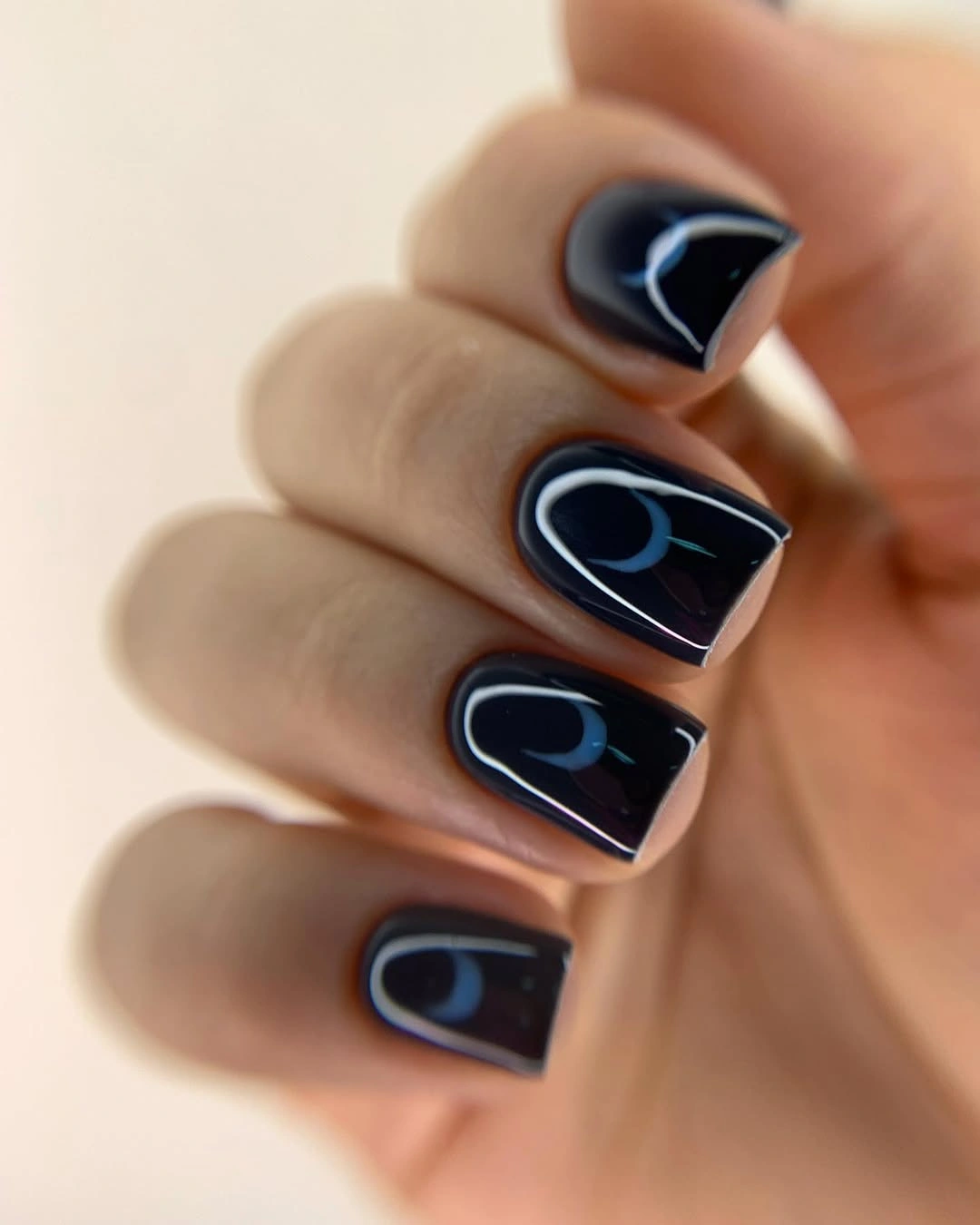 Glossy black square nails with pale curved highlights
