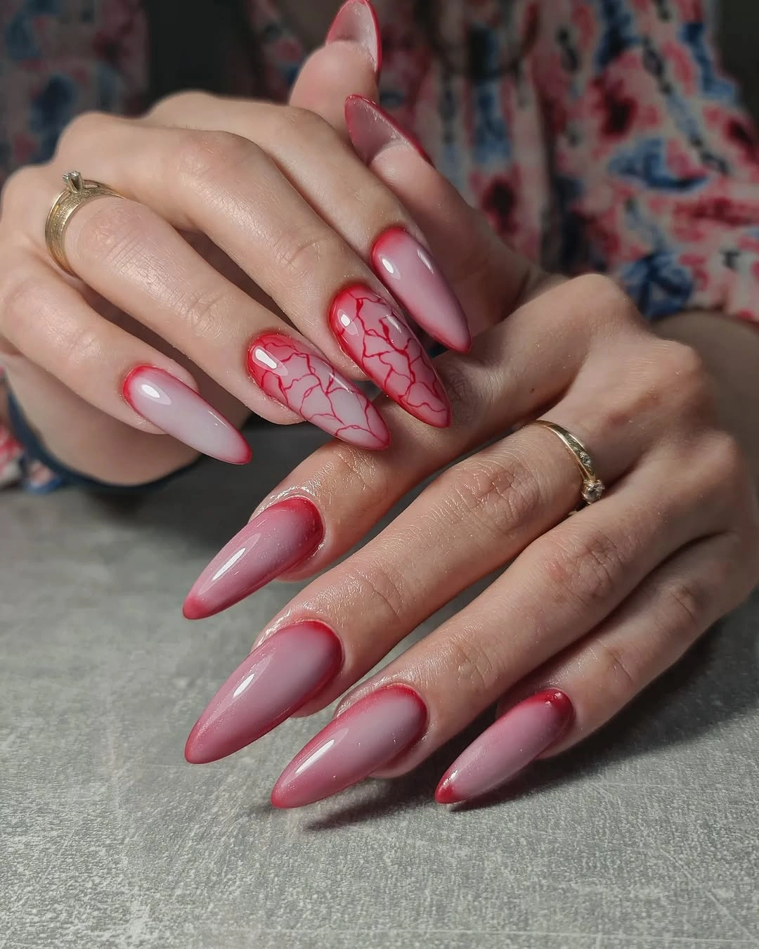 Glossy pink almond nails with red abstract line accents