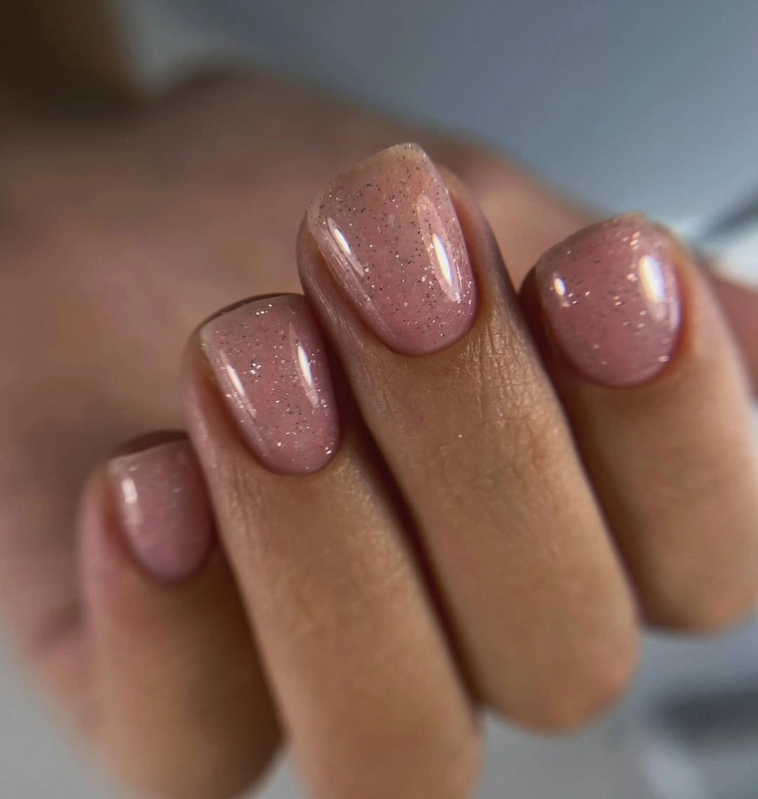 Sheer blush pink rounded nails with fine golden sparkle