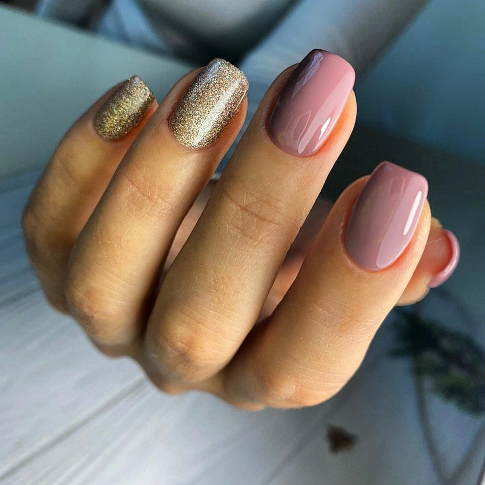 Blush almond nails with warm gold glitter tips