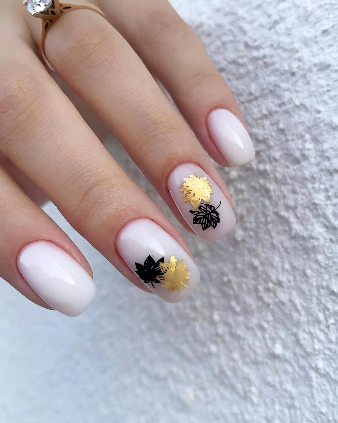 Milky white nails with tiny black and gold seasonal details