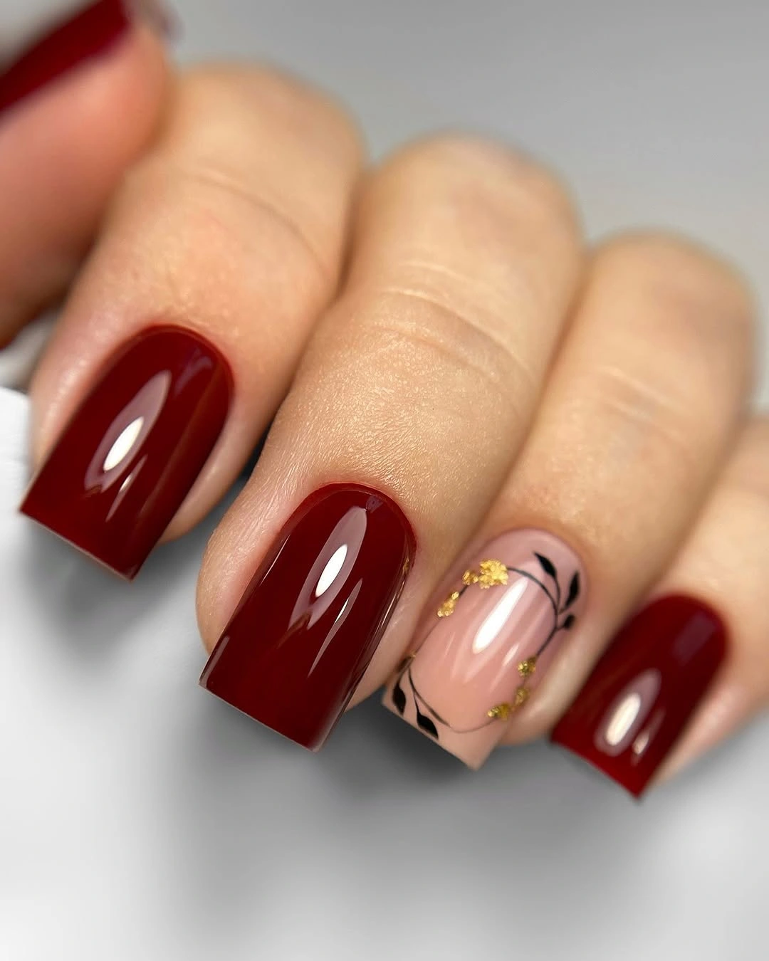 Glossy burgundy nails with blush line-art accent