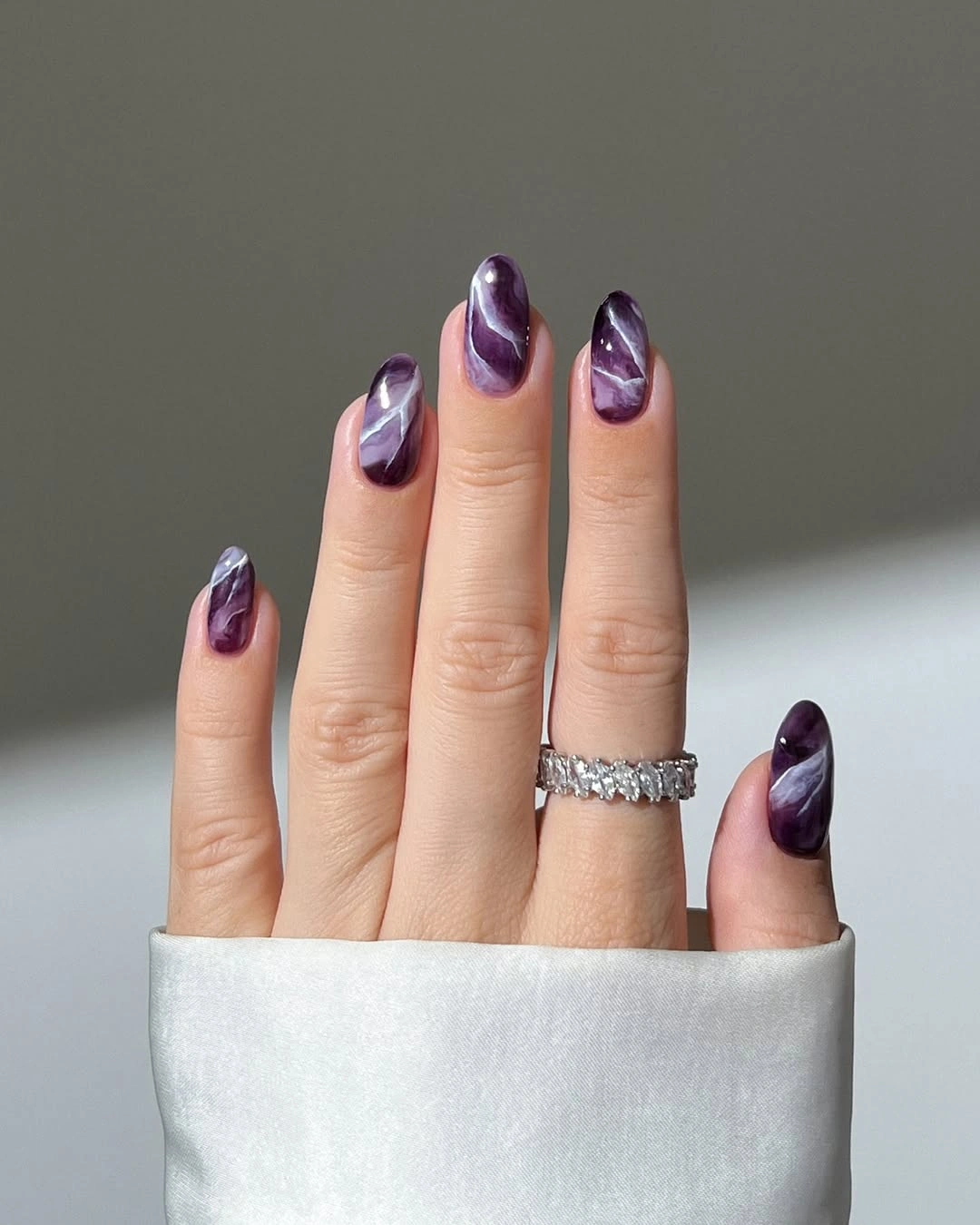 Short rounded purple nails with pale marble lines