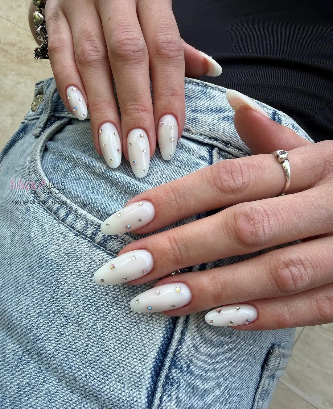 Milky white almond nails with scattered reflective accents