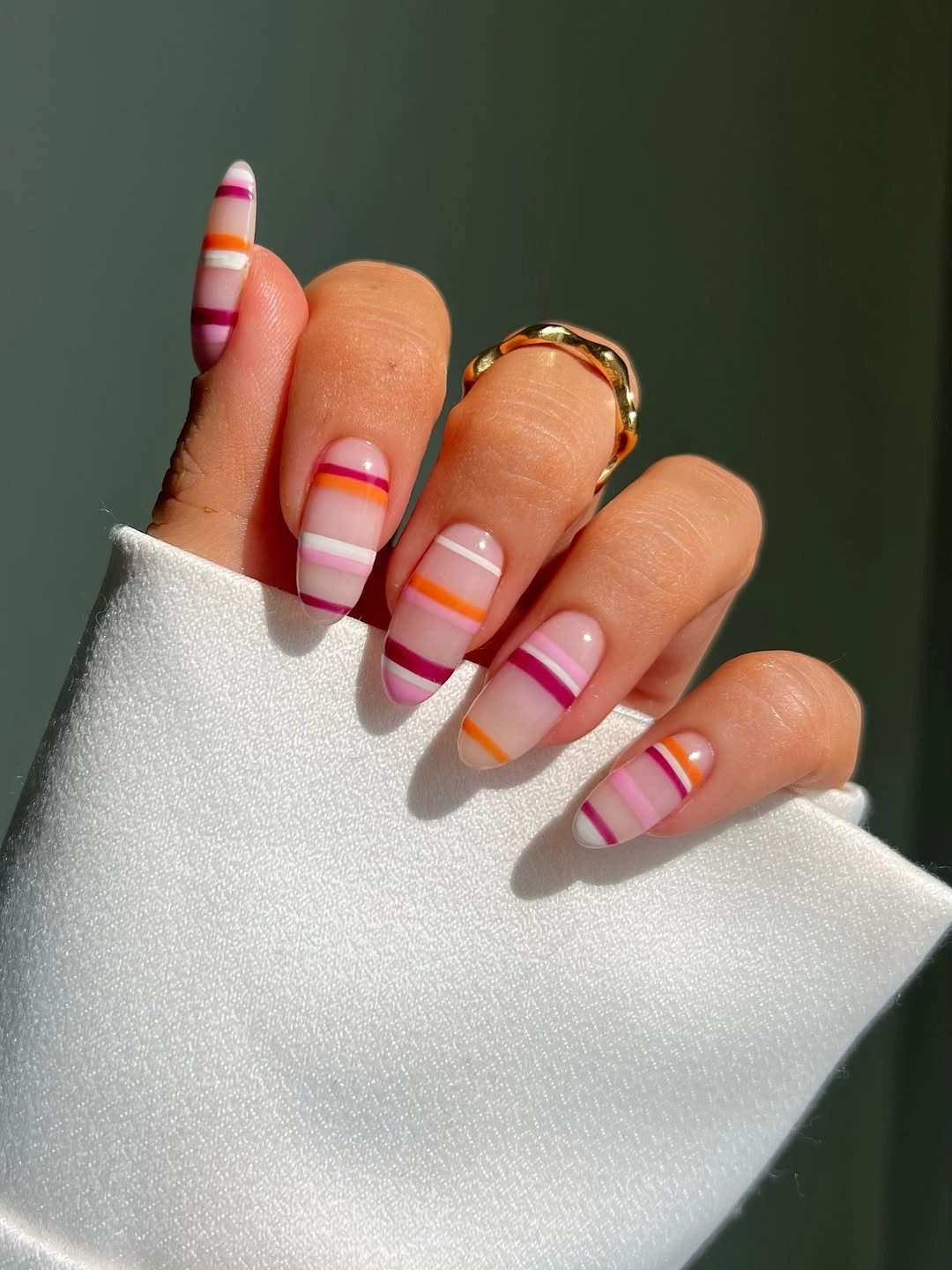 Sheer almond nails with orange and magenta stripes