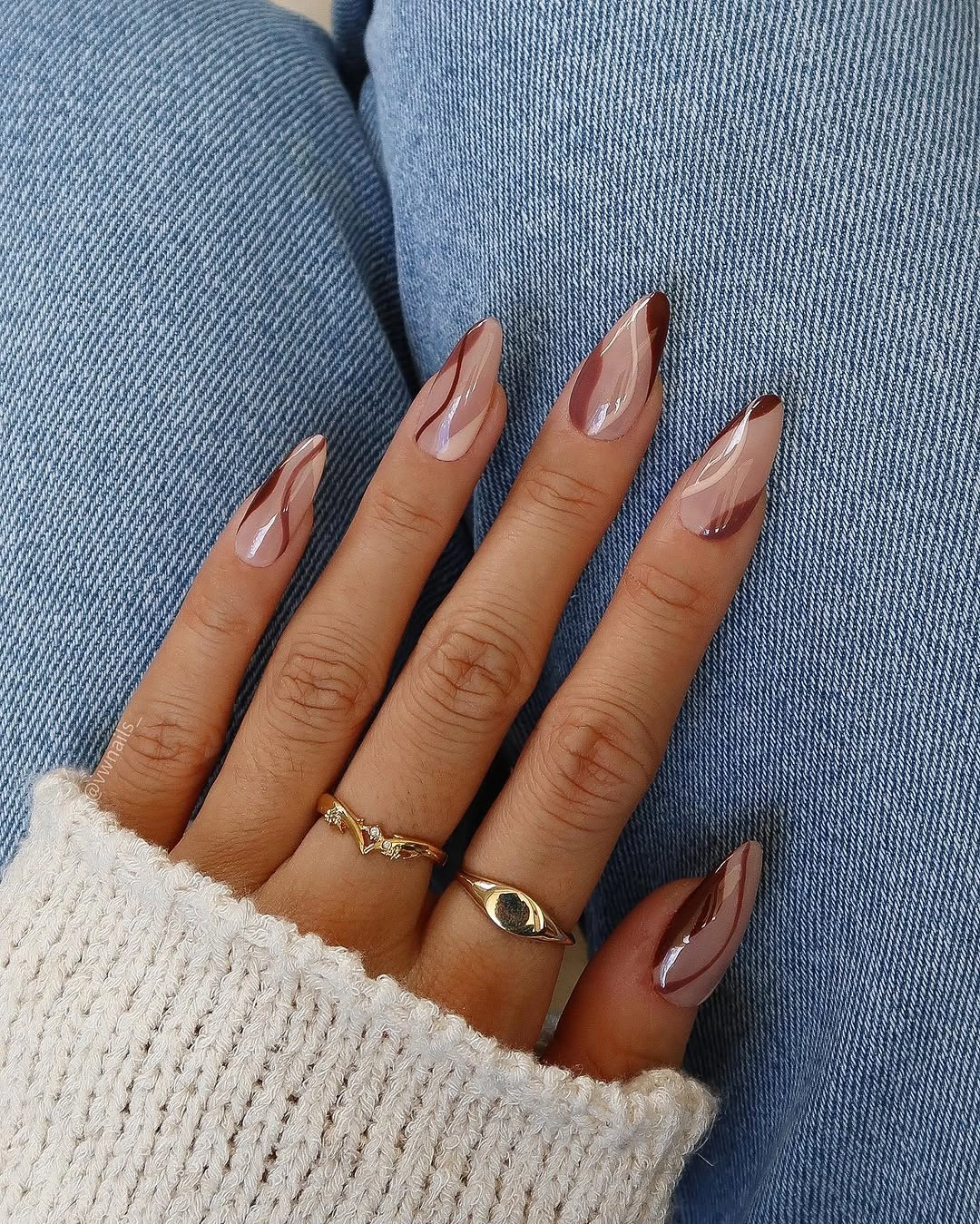 Sheer nude almond nails with curved brown accents