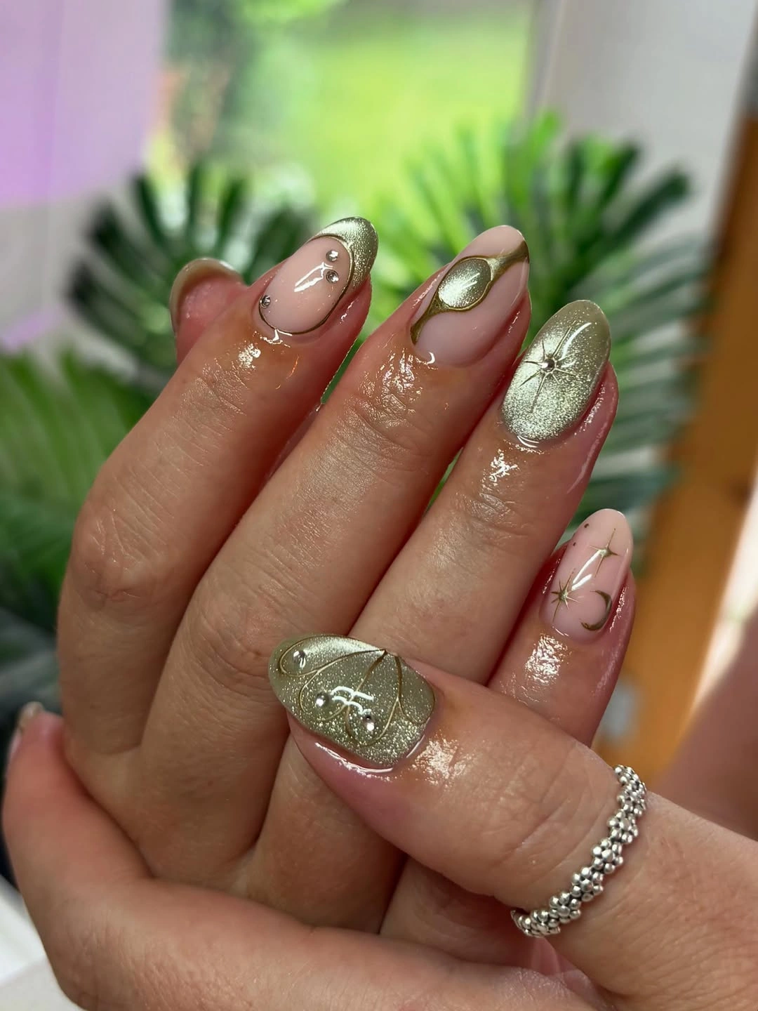 Metallic green gold almond nails with celestial accents