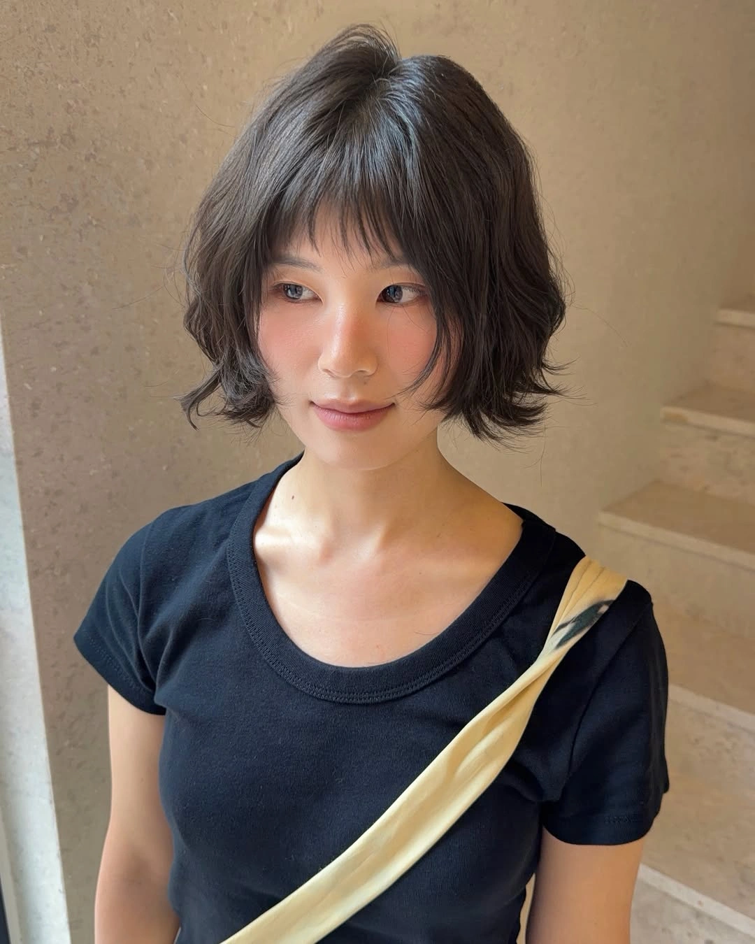 Short rounded brown bob with airy layers and wispy bangs