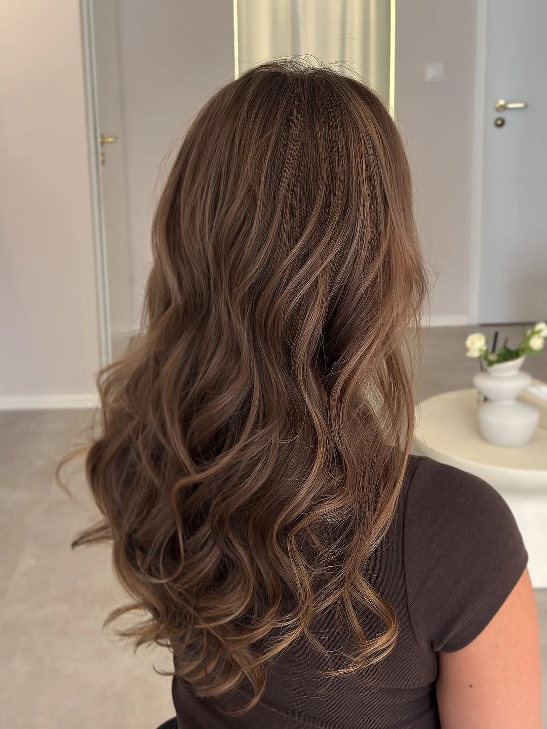 Long medium warm brown hair with soft rounded waves and layers