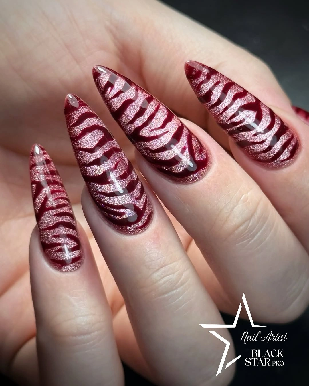 long pointed burgundy nails with sweeping pale curved stripes
