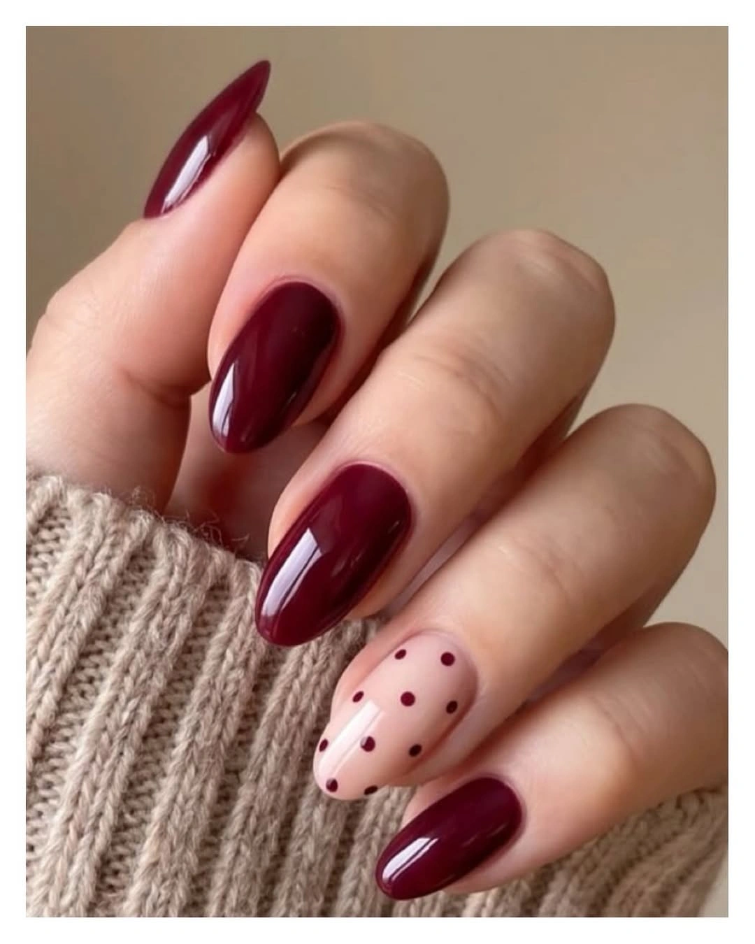medium burgundy almond nails with one dotted blush accent