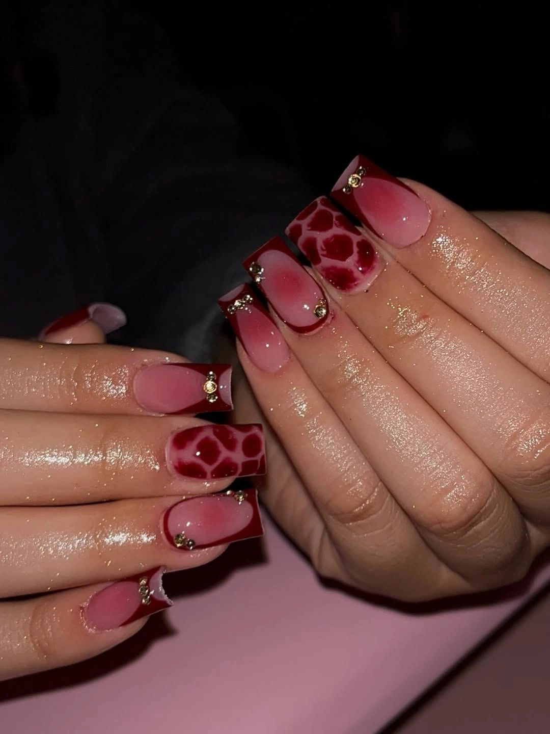 medium blush nails with burgundy patches and small accents