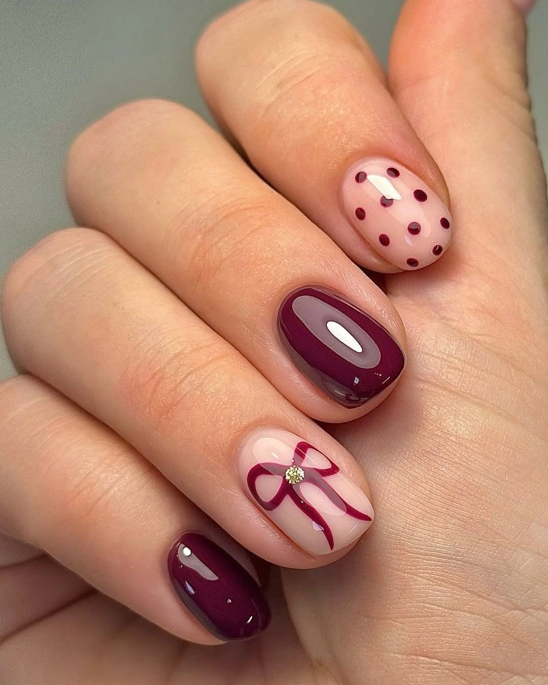 short burgundy nails with nude dotted and curved accents