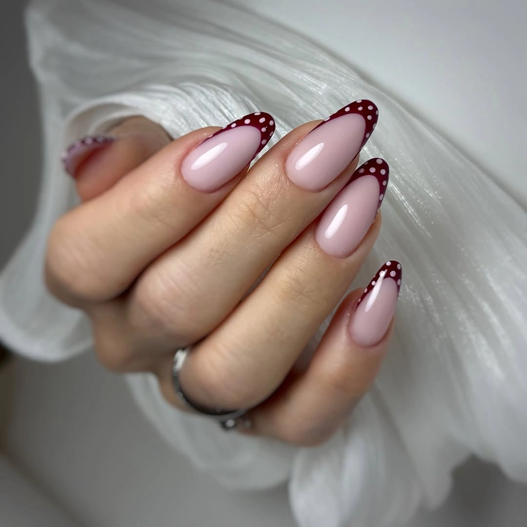 pale pink almond nails with dotted burgundy French edges