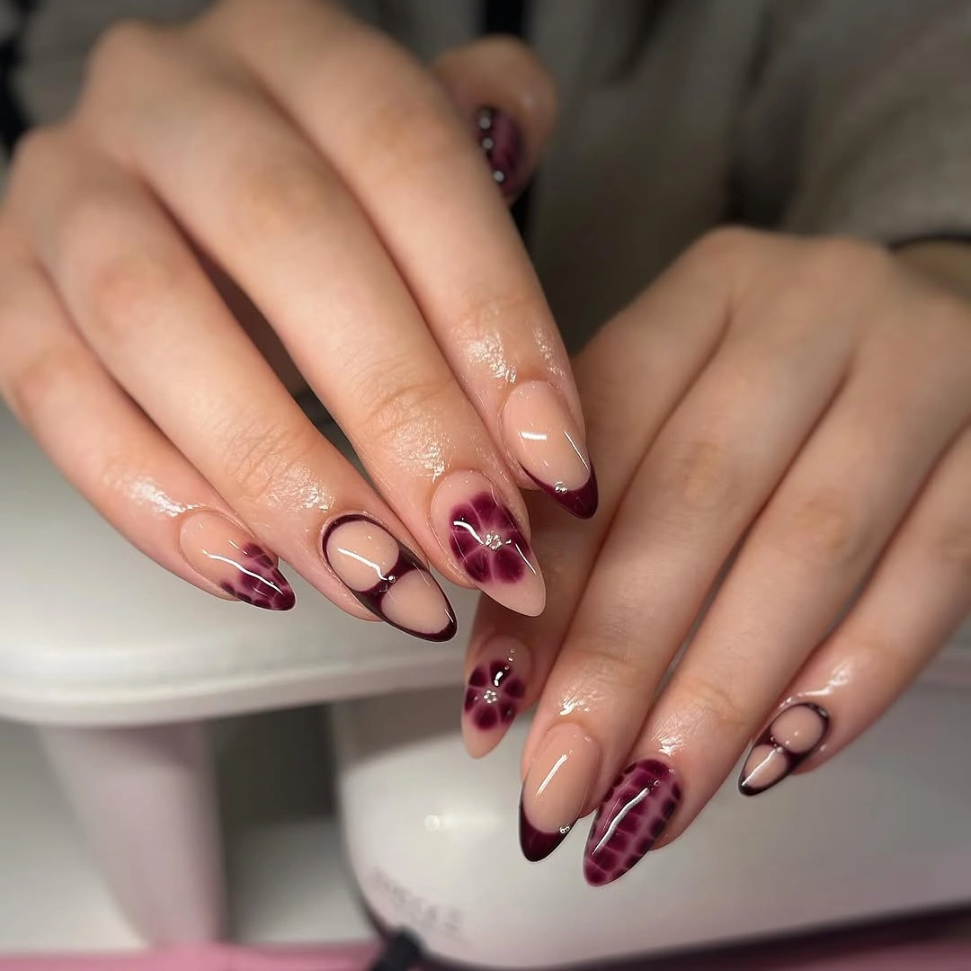 medium almond nude nails with burgundy curves and dark patterned tips