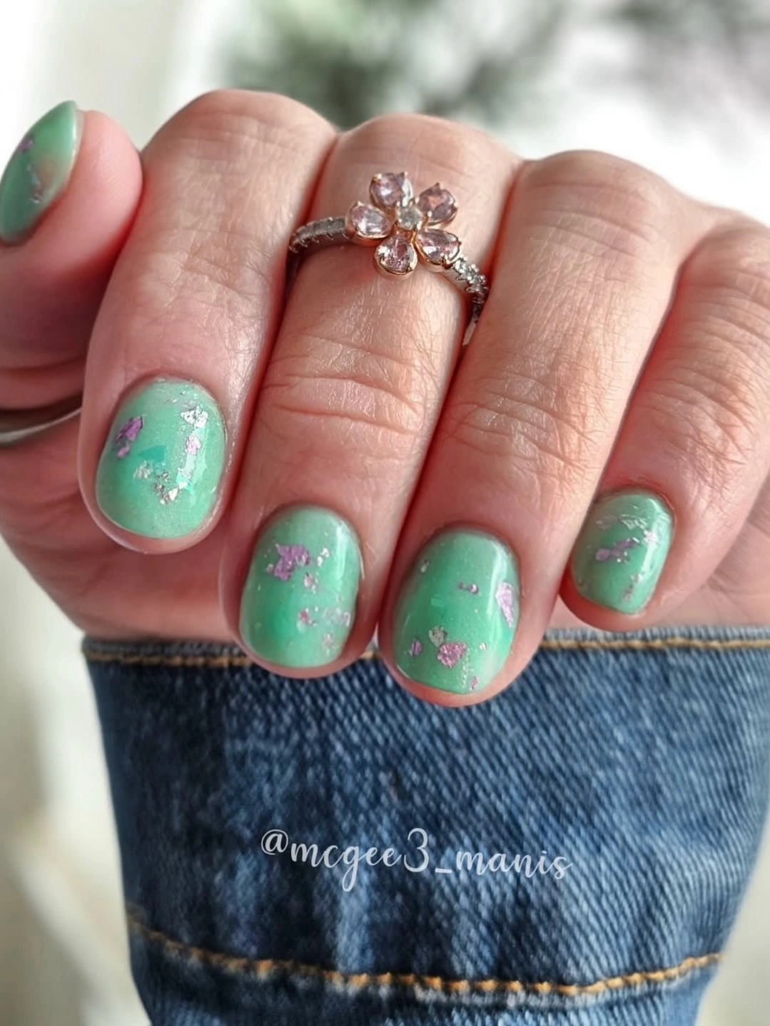Short mint nails with small dark speckles and deep accent edges