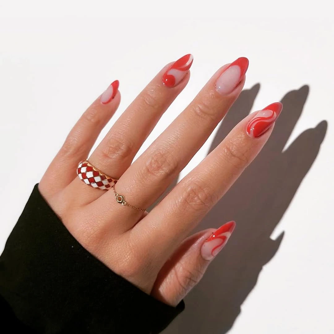 Short nude almond nails with irregular warm red wavy French tips