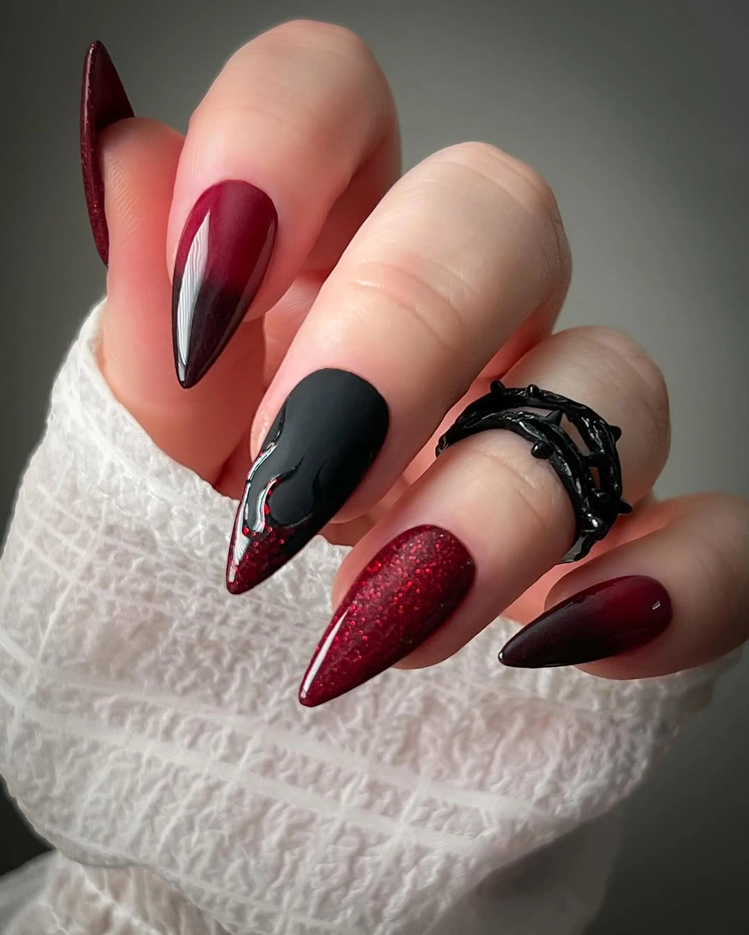 Extra-long stiletto nails with burgundy black and nude negative-space curves