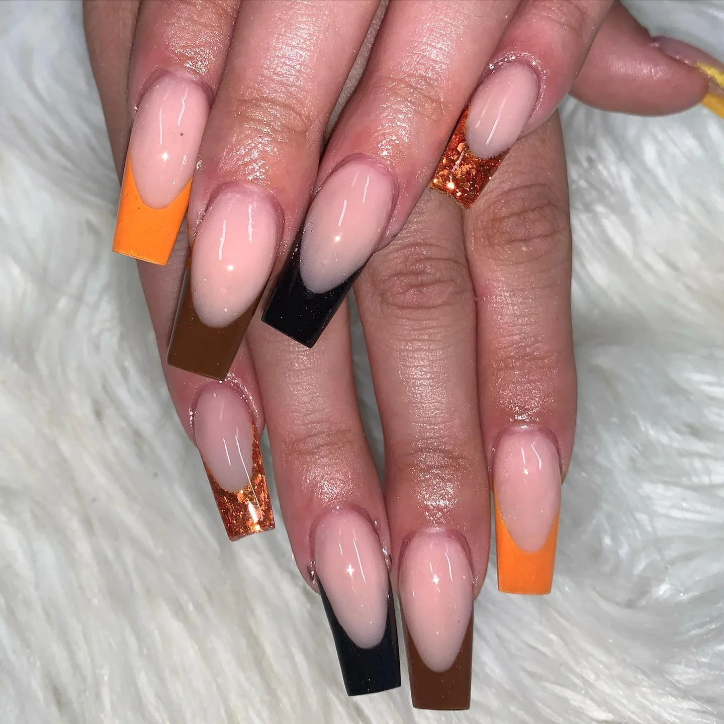 Long coffin nails with alternating orange black and glitter French tips