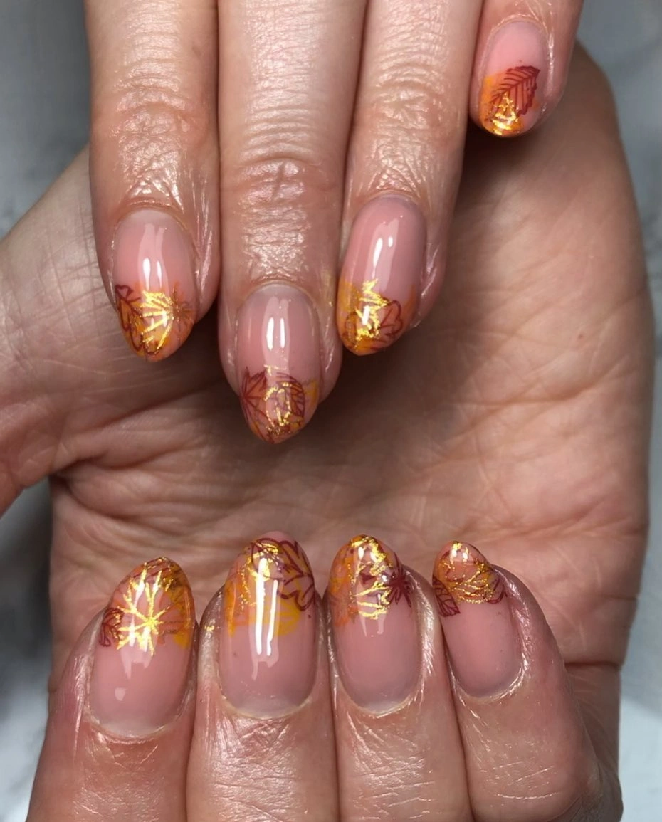 Short rounded pink nude nails with warm gold French accents