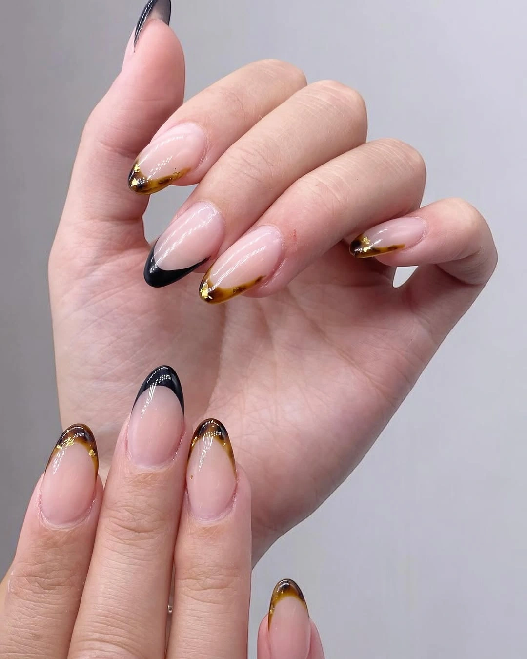Medium almond nude nails with black and gold outlined French tips