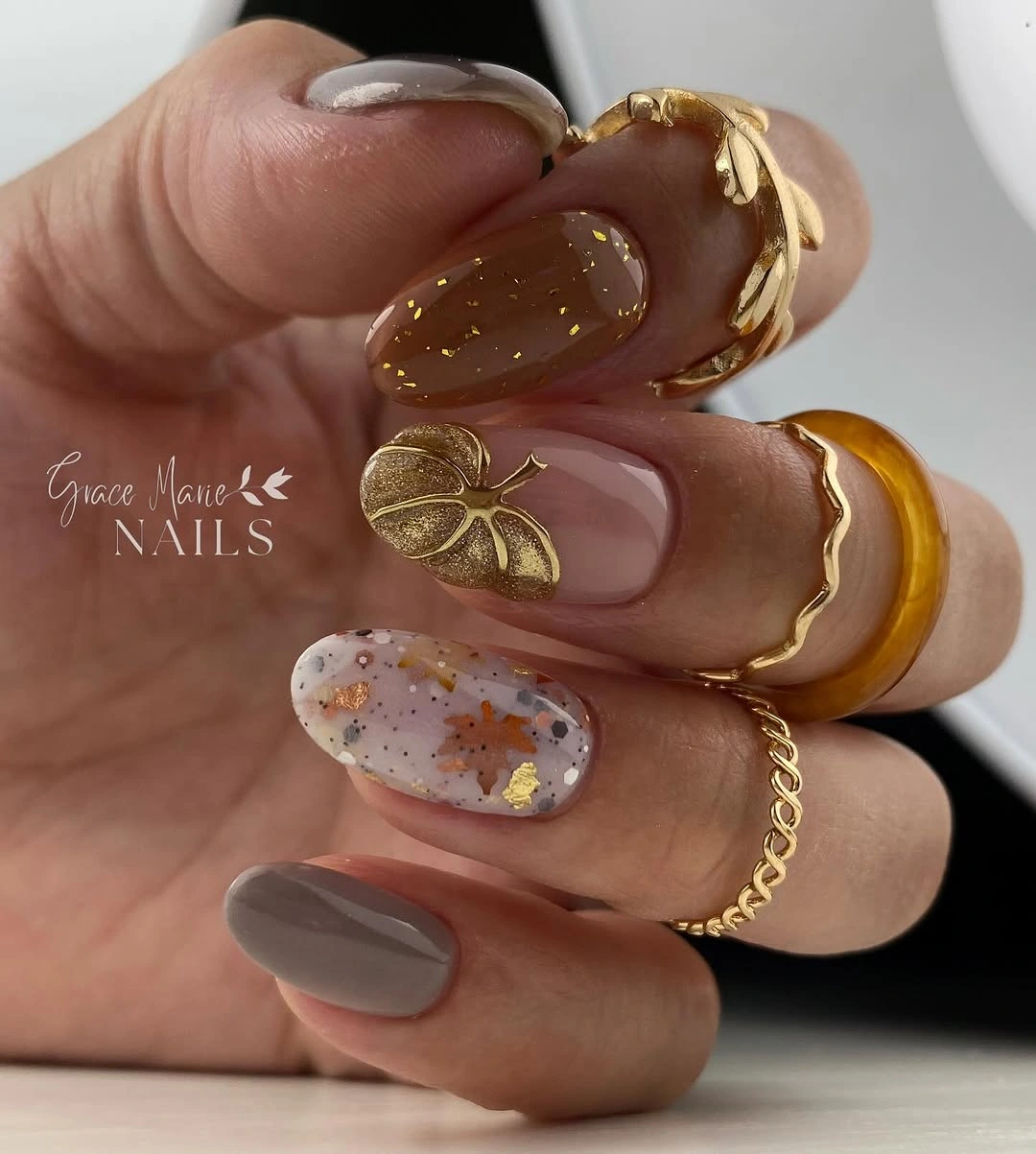 Brown almond nails with nude space and gold floral detail