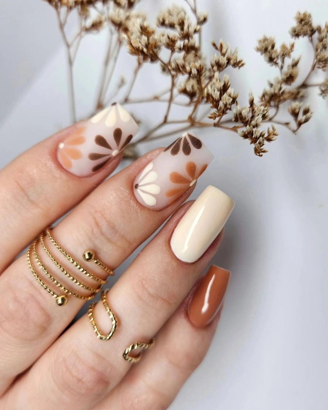 Warm cream square nails with brown leaf and flower shapes