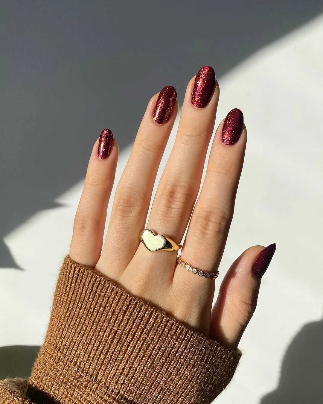 Deep berry shimmer oval nails in sunlight