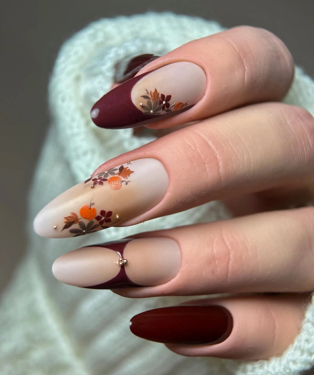 Long almond cream nails with berry tips and orange floral details