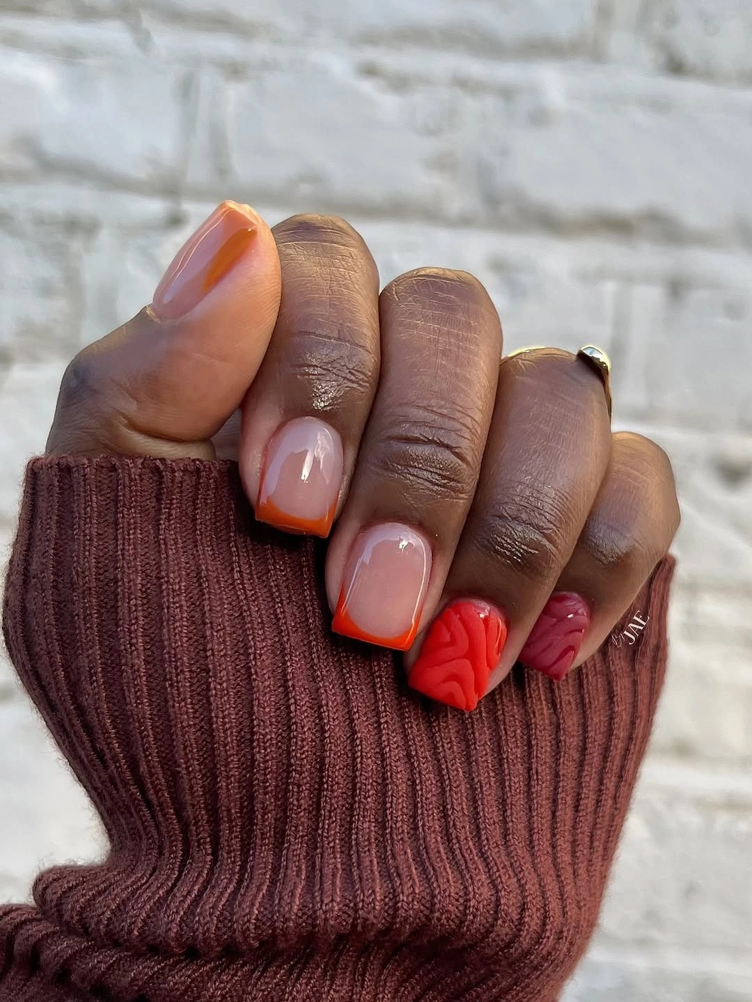 Short-to-medium square nails with nude bases and red-orange tips
