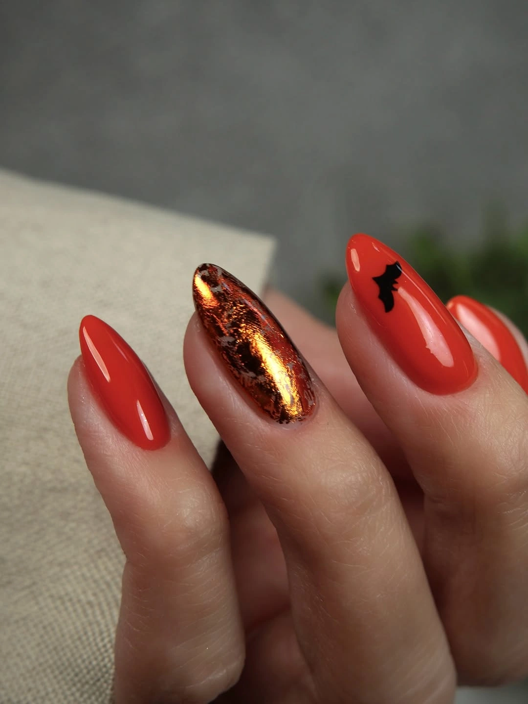 Medium almond glossy red nails with one copper metallic accent
