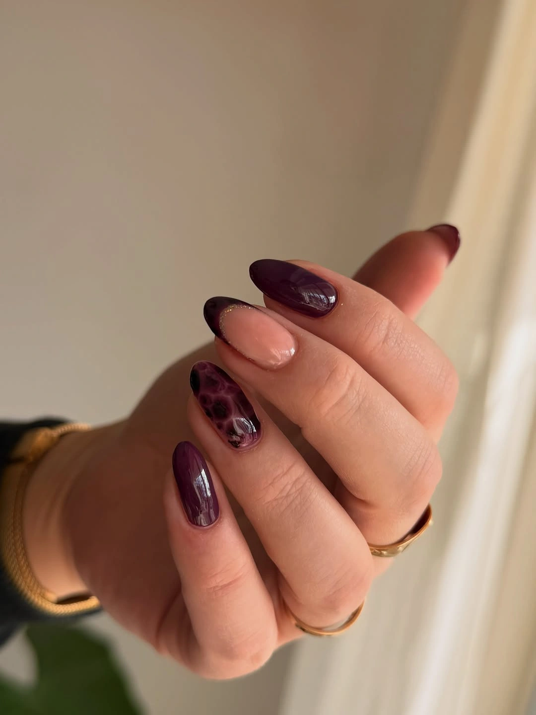 Long almond nails in dusty rose and deep plum with one patterned accent