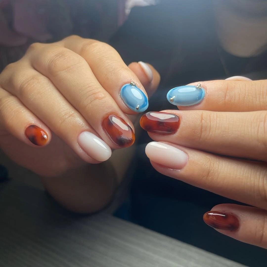 Short rounded nails in chocolate brown pale pink and bright blue