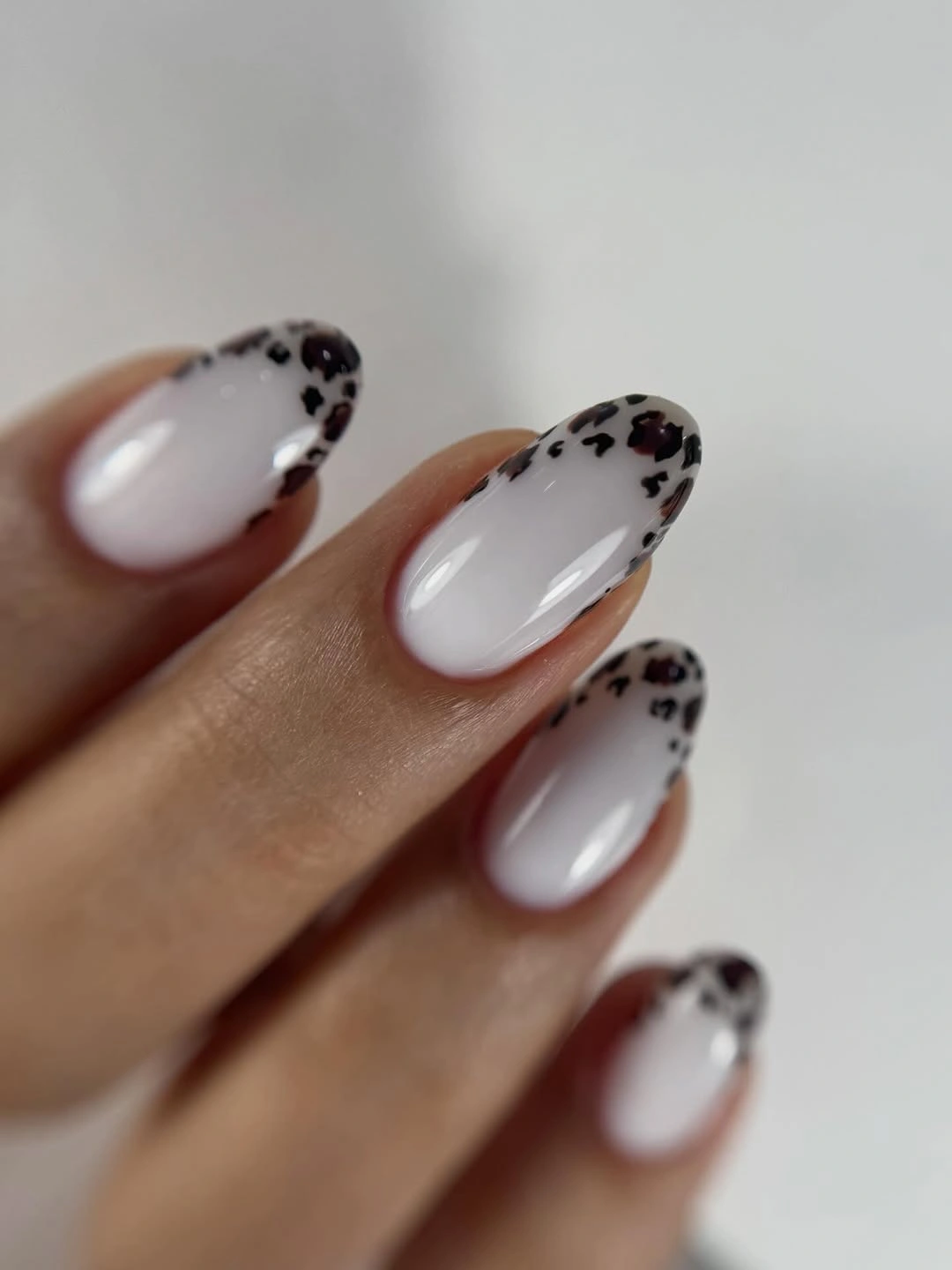 Milky white almond nails with black speckled French tips