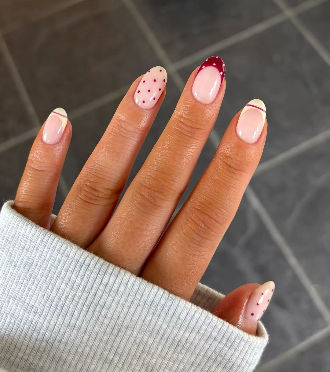 Medium almond pale pink nails with small red and green accents