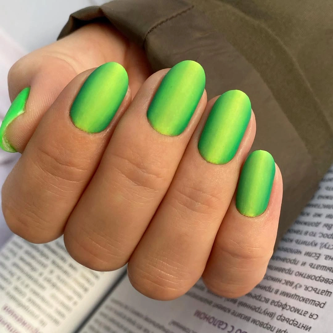 Short oval nails in a neon lime and yellow green blend