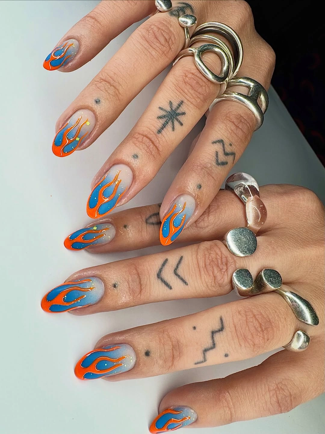 Long almond nails with electric blue and orange curved linework