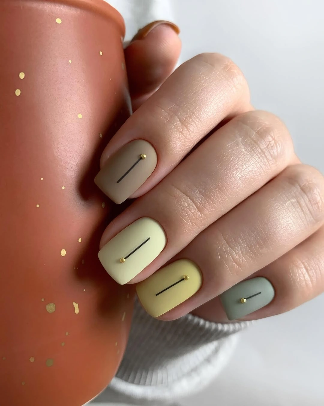 Short pastel squoval nails with thin lines and tiny gold studs
