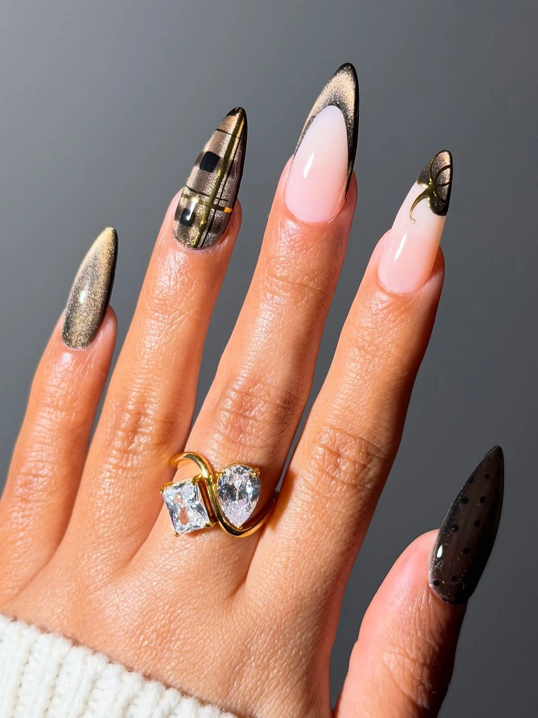 Long neutral nails with metallic bands and dark accents