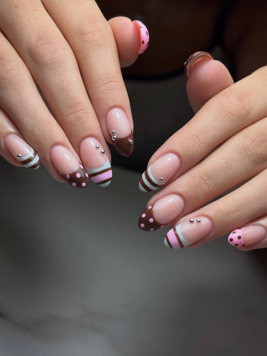 Pink almond nails with brown blue and white striped tips