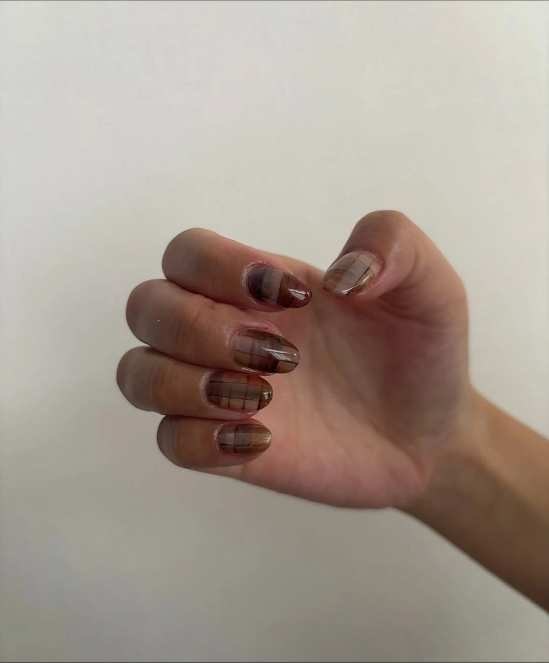 Rounded brown nails with translucent plaid pattern